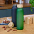A drink bottle in matte green with a wooden lid stands next to a black bottle on a wooden surface.