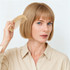 A bamboo small comb held by a person with blonde hair, styled in a bob, wearing a beige shirt.