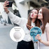 Two women taking a selfie while holding a 20cm foldable reflective fan with a blue tropical design and a reflective backer.