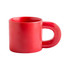A red ceramic coffee mug with a unique handle design and a glossy finish. The mug features a logo.