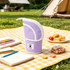 A lavender expandable pencil case with a white zipper, placed on a picnic blanket beside notebooks and snacks.