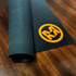 A black deluxe fabric top counter mat with a textured finish and an orange logo.