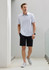 A light grey short sleeve polo shirt paired with black shorts and grey sneakers. The model is standing in a modern setting.