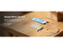 A slim, rectangular grey power bank connected to a phone on a wooden table. The phone displays a charging icon.
