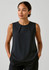 A sleeveless black blouse featuring pleat detail, styled with a simple round neckline.