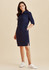 A navy blue shirt dress featuring a button-up front, belted waist, and side pockets, paired with white sneakers.