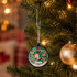 A hanging decorative ball featuring a Santa scene with a green background, accented with white and red details.