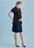 A pregnant woman wearing a black top and a navy maternity skirt, standing against a light blue background.