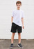 A young boy poses in a white t-shirt paired with black sports shorts, standing against a white wall.