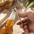 A drink bottle with a silver cap and a wooden bottle opener, set on a textured surface alongside snacks.