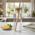 A glass drink bottle with a bamboo lid and straw, filled with water, situated on a marble surface with lemon slices and mint.