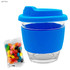 A reusable glass coffee cup with a light blue silicone lid and sleeve, accompanied by a pack of colourful jelly beans.