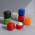 A collection of colourful lip balm cubes in black, white, green, red, blue, and orange, some opened to reveal the balm.