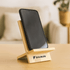 A bamboo phone stand featuring a sleek design, holding a smartphone, with a logo on the base.