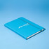 A blue A5 notebook with an elastic band closure and a branded logo on the cover.