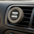 A round, grey magnetic car vent mount with a logo, designed for holding phones.