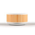 A wireless speaker and charger with a bamboo and white design, featuring a circular shape and vented base.