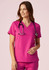 A women's pink V-neck scrub top is displayed, featuring short sleeves and a classic fit, with a stethoscope around the neck.