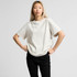 A light beige, oversized t-shirt featuring short sleeves and a relaxed fit, with a logo visible.