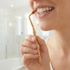 A woman using a gum stimulator, cleaning along her gum line.