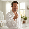 A view of a man in a bathrobe holding a gum stimulator
