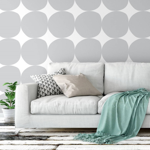 Gray couch with mint green throw blanket in front of removable gray circles wallpaper