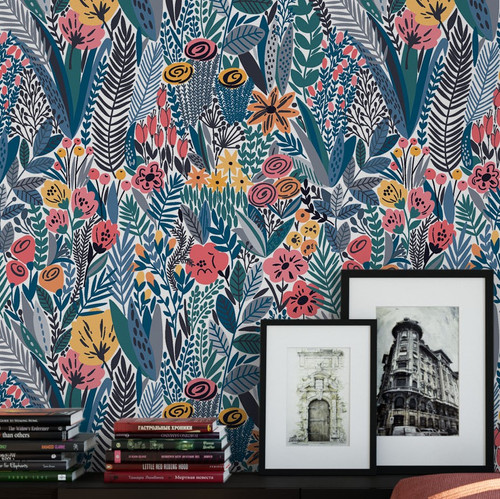 A shelf with books and photographs with brightly colored abstracted flower wallpaper