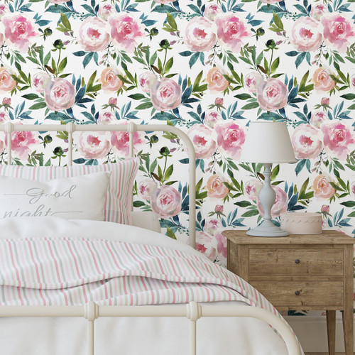 A close up view of a girls room with a metal bed, striped bedding, a side table with a lamp and Watercolor peony floral removable wallpaper