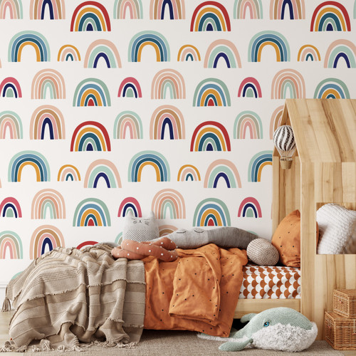 A child's bedroom with a wooden bed with rust colored bedding and colorful rainbow peel and stick wallpaper