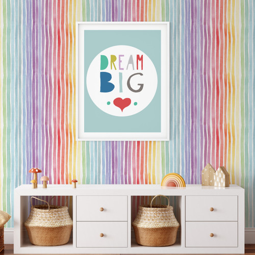 Watercolor rainbow striped wallpaper behind a credenza with toys and a poster that says "dream big"