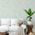 Cherry blossom wallpaper on an aqua background in a room with a white couch and a large plant.