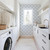 Paperbird Home Blue Blockprint Peel and Stick Wallpaper featuring a hand-stamped floral design in navy blue, styled for a modern laundry room or kitchen backsplash.