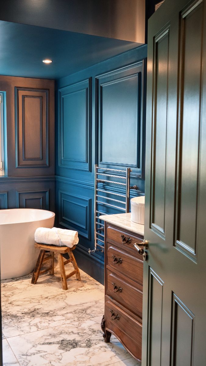 Luxurious bathroom with navy blue full-wall wainscoting, complemented by rich wooden accents creating a spa-like atmosphere