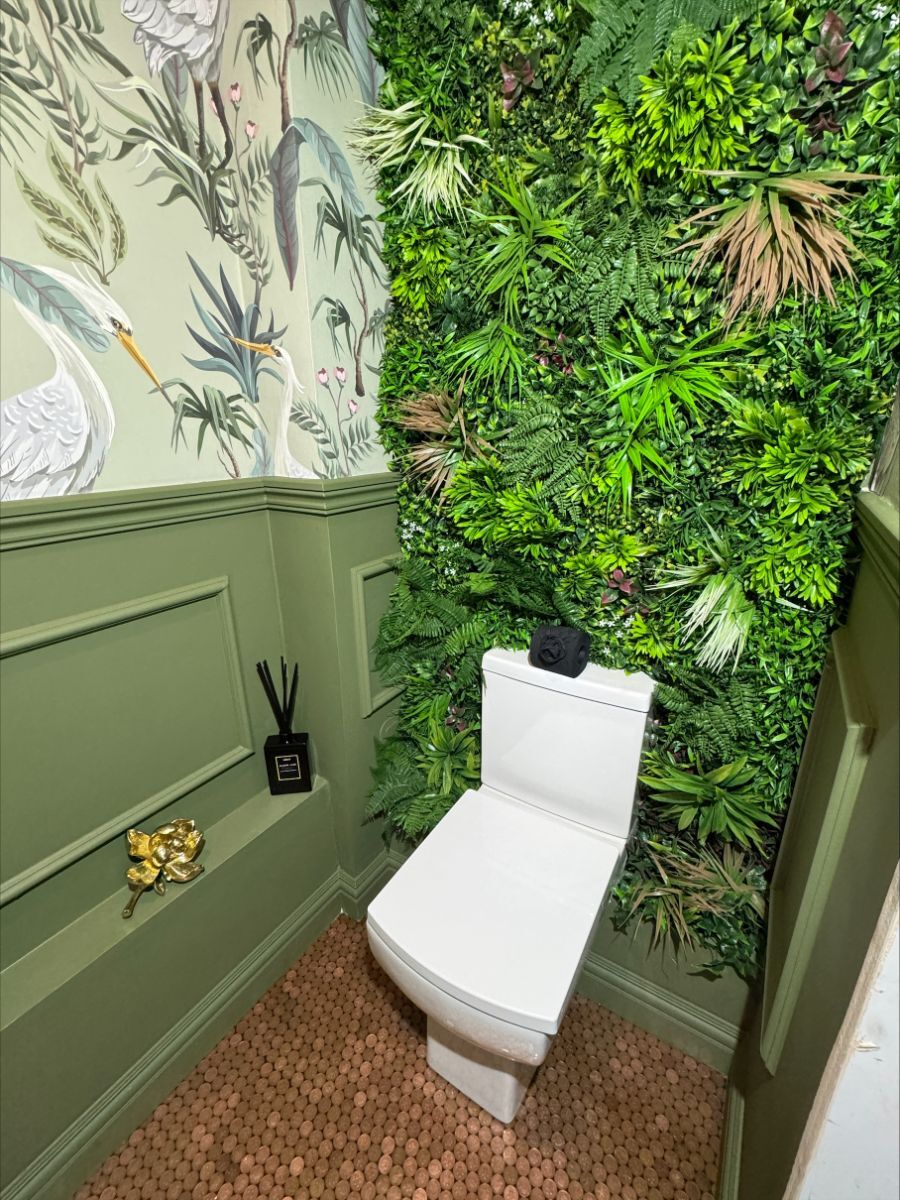 Angled view of the eclectic bathroom showing the green wainscoting and floral wall panel from a different perspective