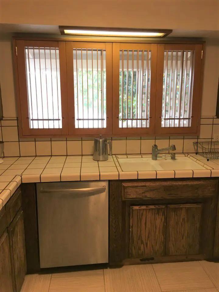 Before renovation: Kitchen corner showing cluttered microwave and refrigerator area with poor visual flow