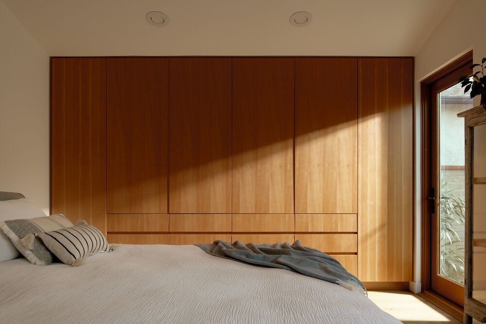Bedroom wardrobe with vertical grain wood panelling demonstrating Japandi craftsmanship and functional minimalism
