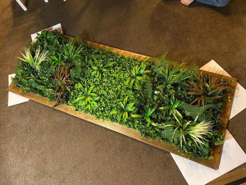 Completed artificial green wall panel laid flat showing full foliage coverage and frame