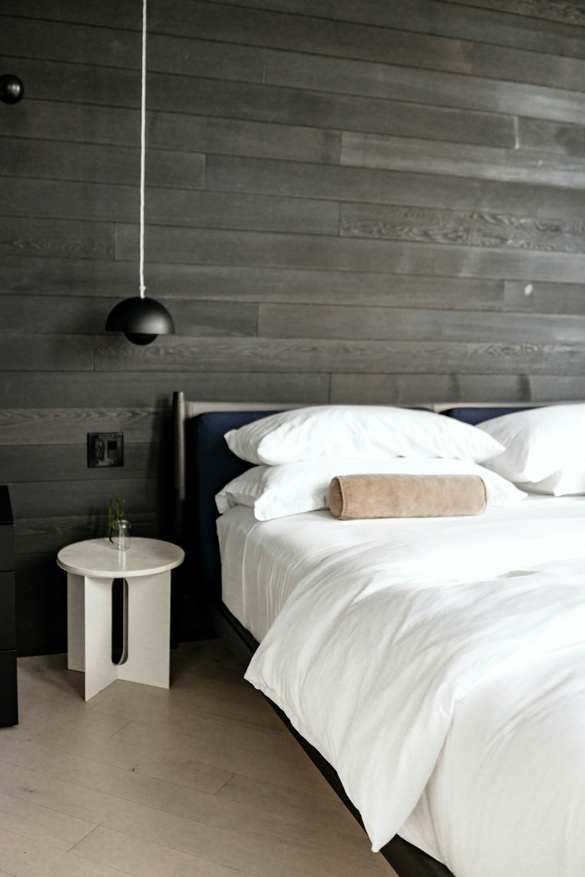 Horizontal dark walnut wood slat panelling with pendant lighting and crisp white bedding