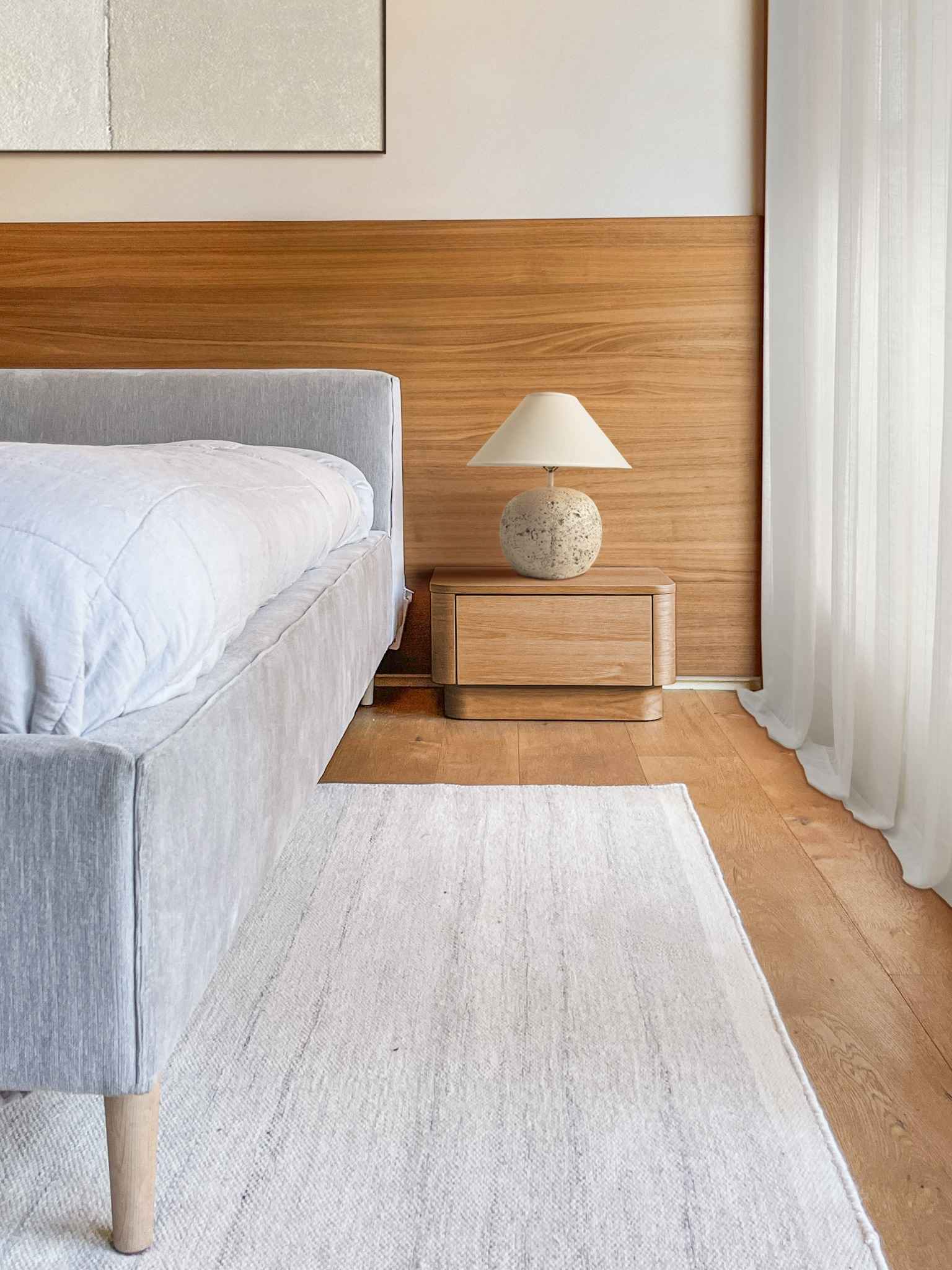 Japandi bedroom detail showing minimalist wooden nightstand and bed with neutral bedding and functional design