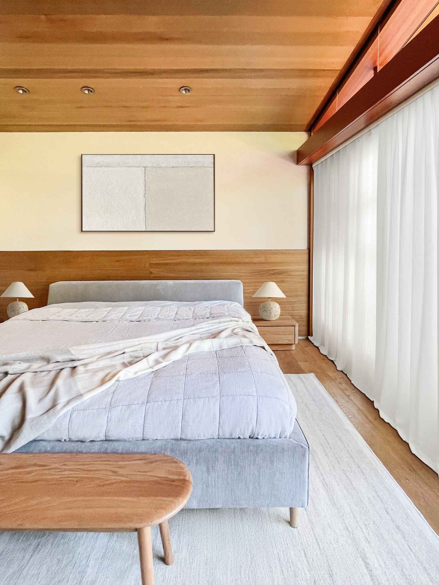 Japandi primary bedroom with grey bedding, natural wood elements and minimalist functional design
