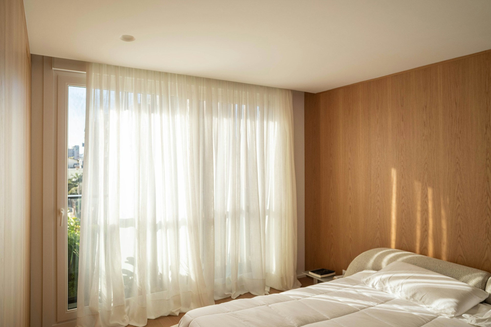 Floor-to-ceiling warm wood panelling with sheer curtains and soft lighting creating cozy atmosphere