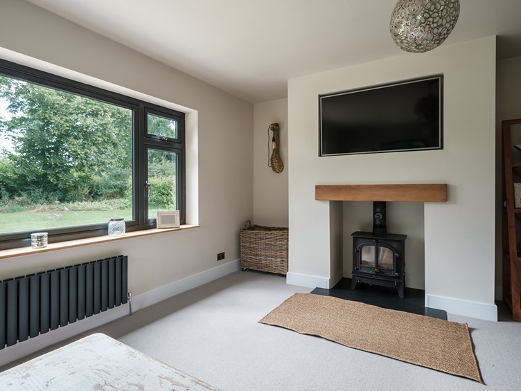 Oak-mantelled media wall featuring a log burner with a wall-mounted TV above.