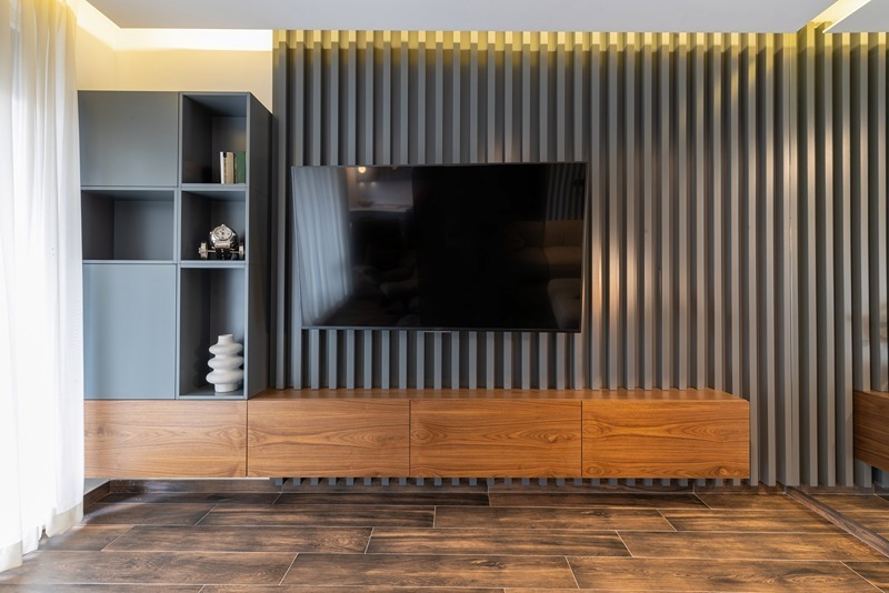 Straight-on view of a media wall in dark slatted wood with coordinating side cabinets.