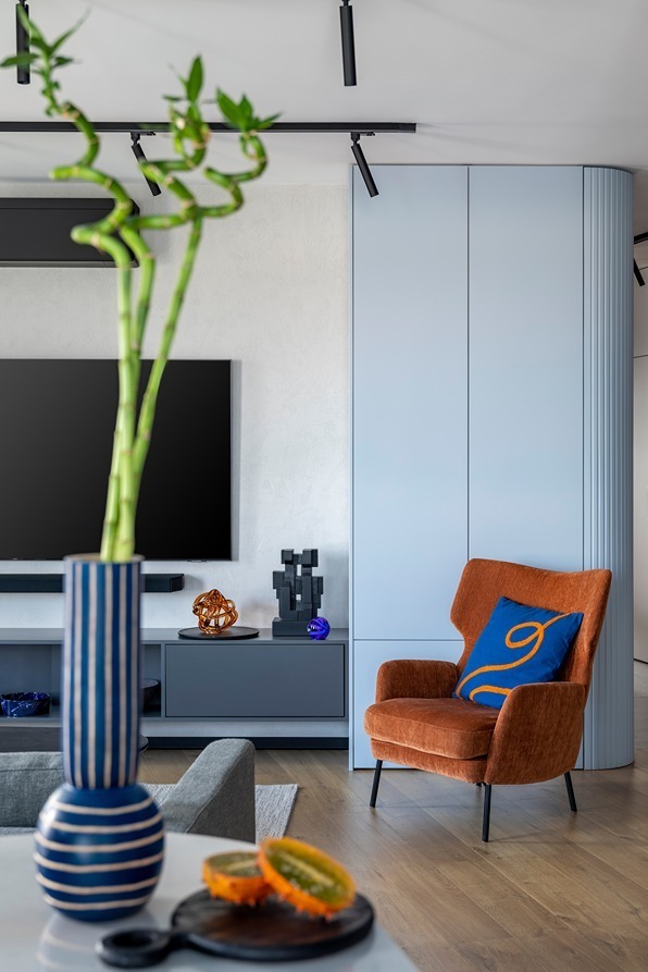 Close-up of sleek media-wall cabinetry alongside an orange accent chair.