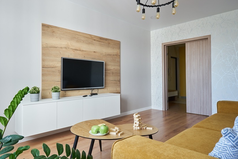 Media wall finished in rich wood panelling above a floating white credenza.