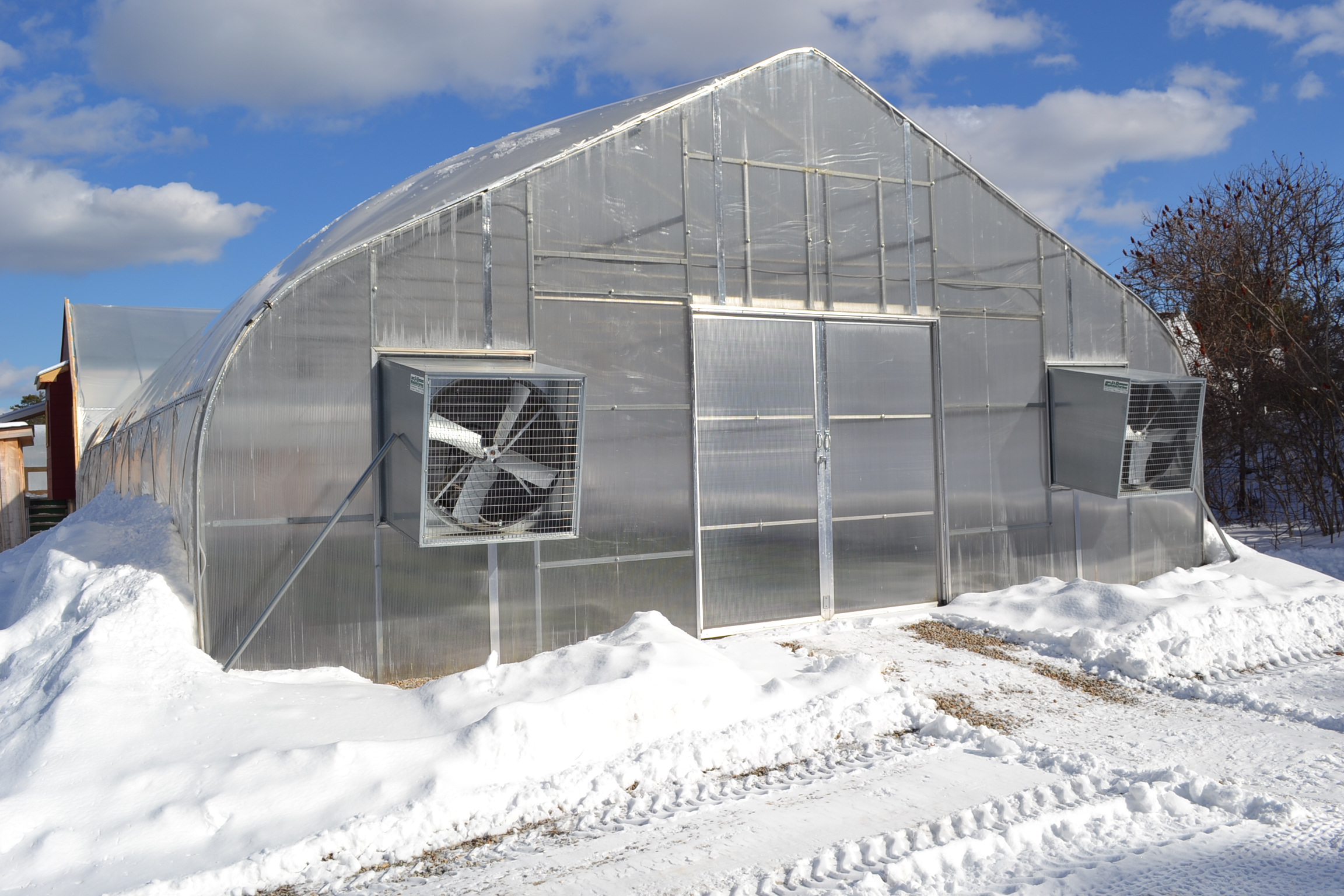 A Rimol greenhouse in the snow with a blue sky background