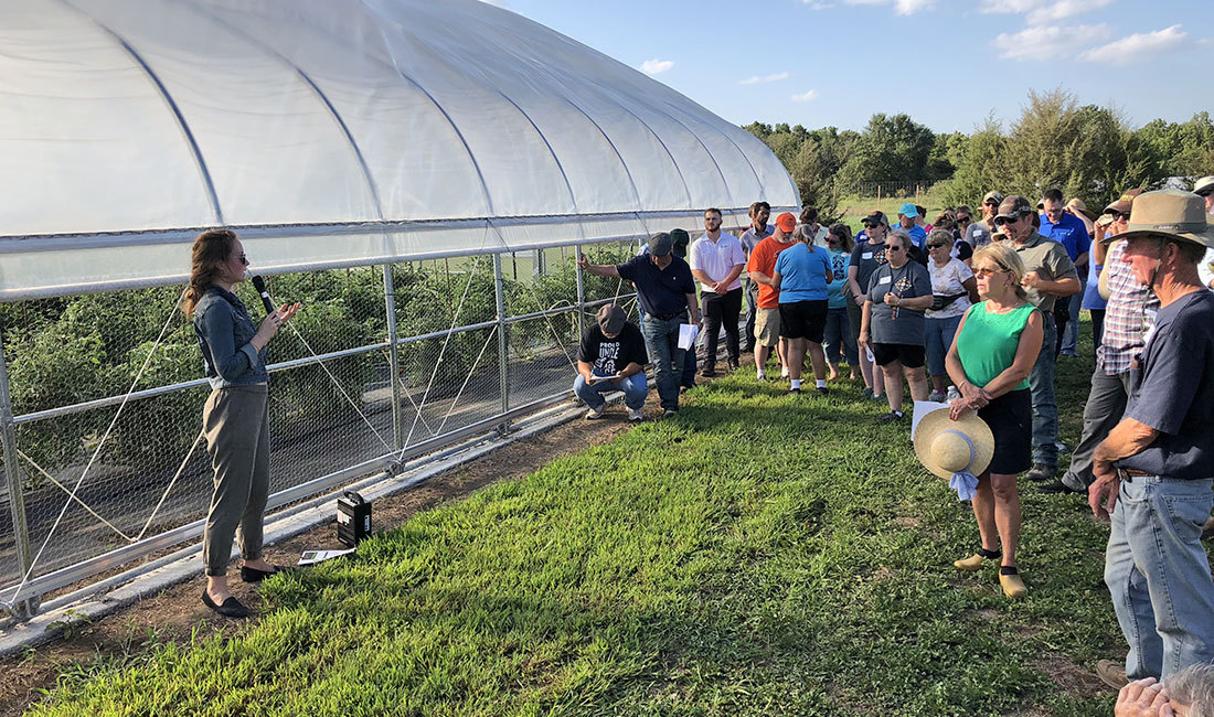 Lady speaking to people in front of a greenhouse