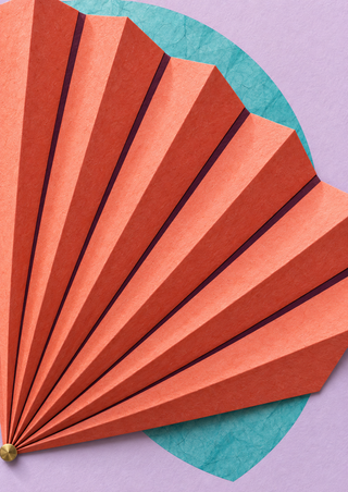 Coral pleated fan with dark plum creases and a gold-colored pivot against a pale lilac background, with a turquoise arc behind it.