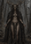 Antler-crowned, skeletal-faced woman in a feathered mantle stands among bare trees as a raven perches on a branch.