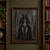 Antler-crowned, skeletal-faced woman in a feathered mantle stands among bare trees as a raven perches on a branch.; frame shown for styling only